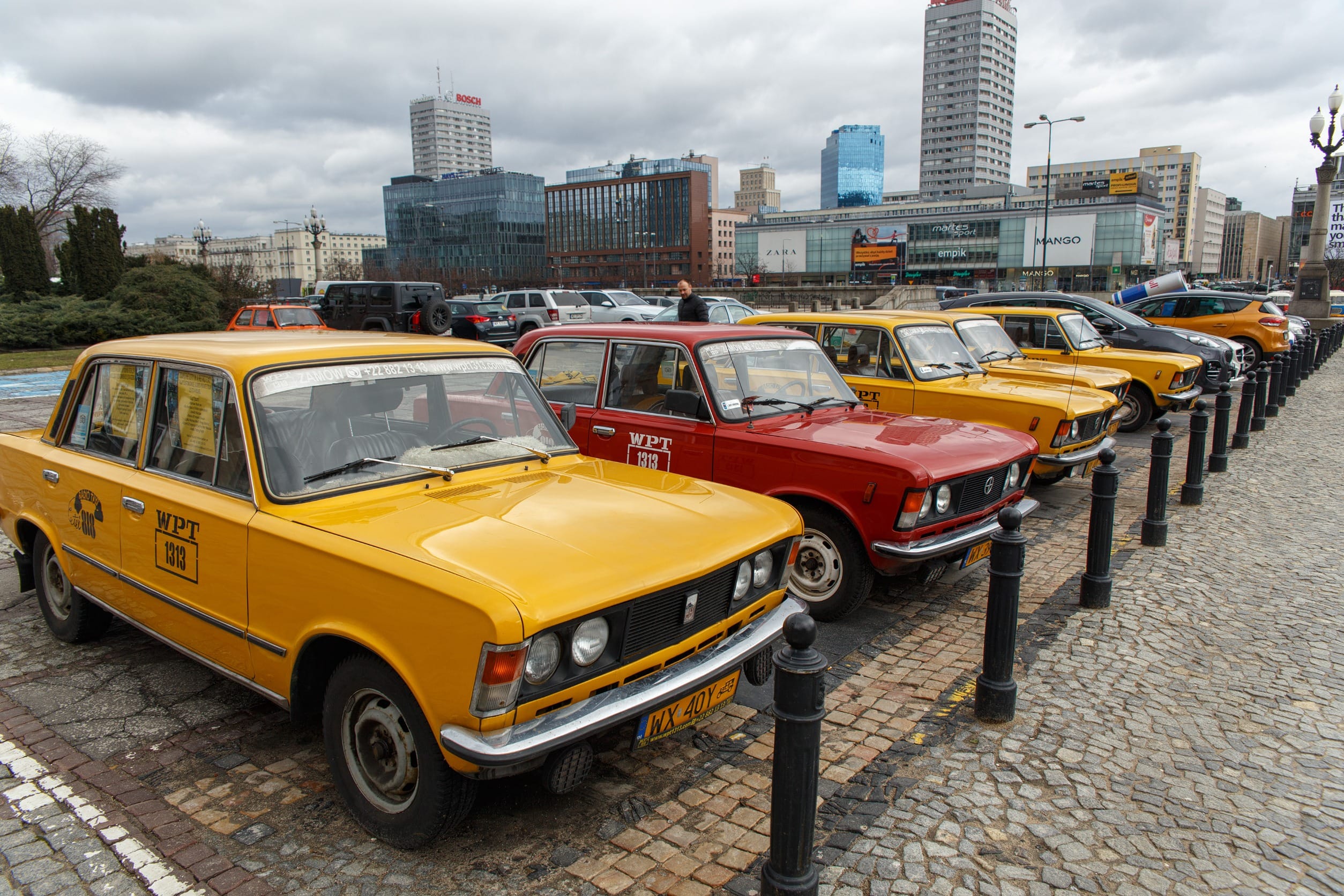 Ряд желтых и красных ретро-такси, на парковке возле Дворца культуры и науки в Варшаве