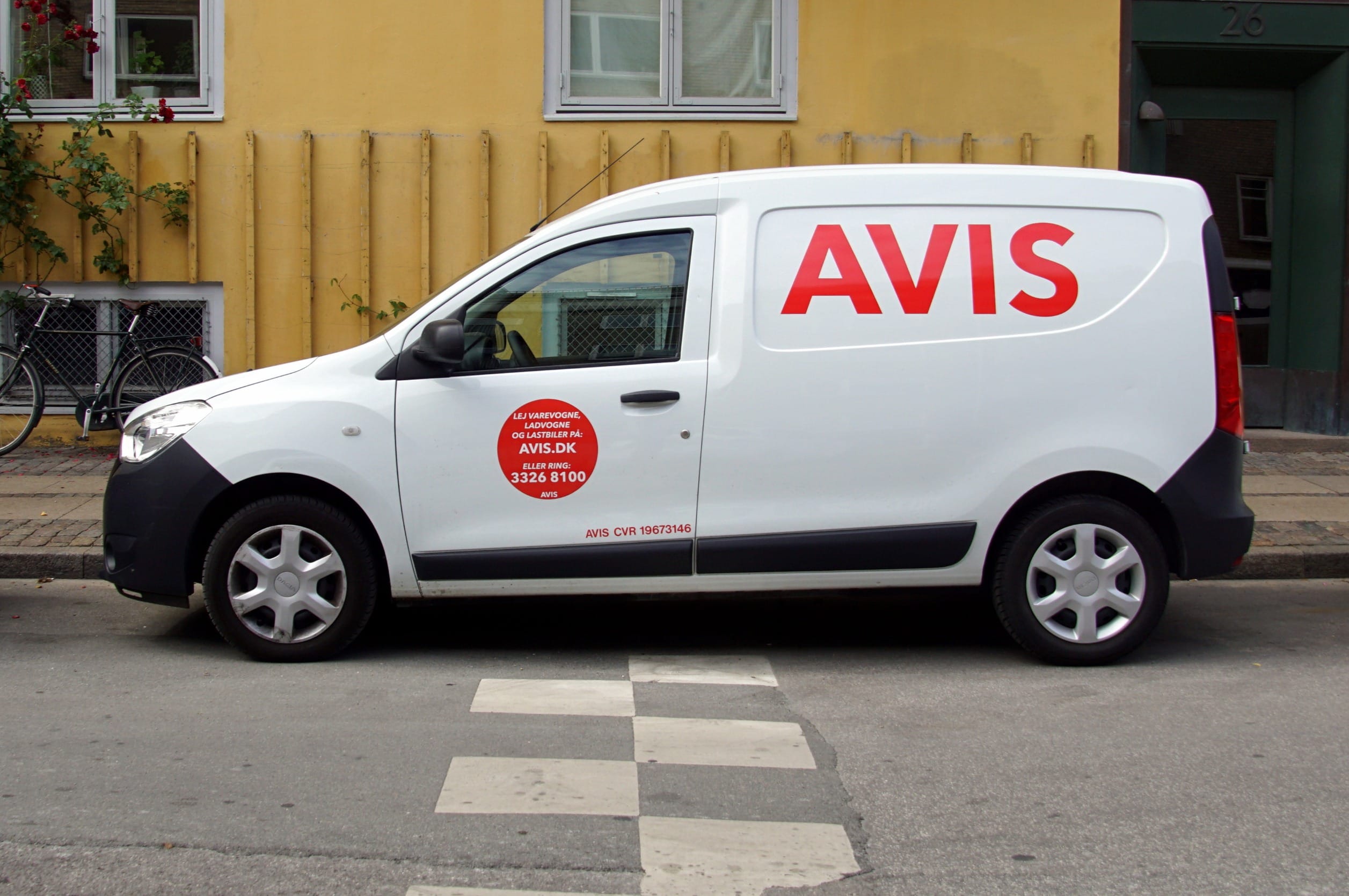 Белая арендованная машина AVIS припаркована на обочине дороги в Копенгагене